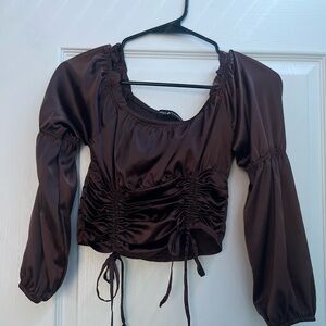 A silk, brown top with two ties in the front and ruffles in the back.